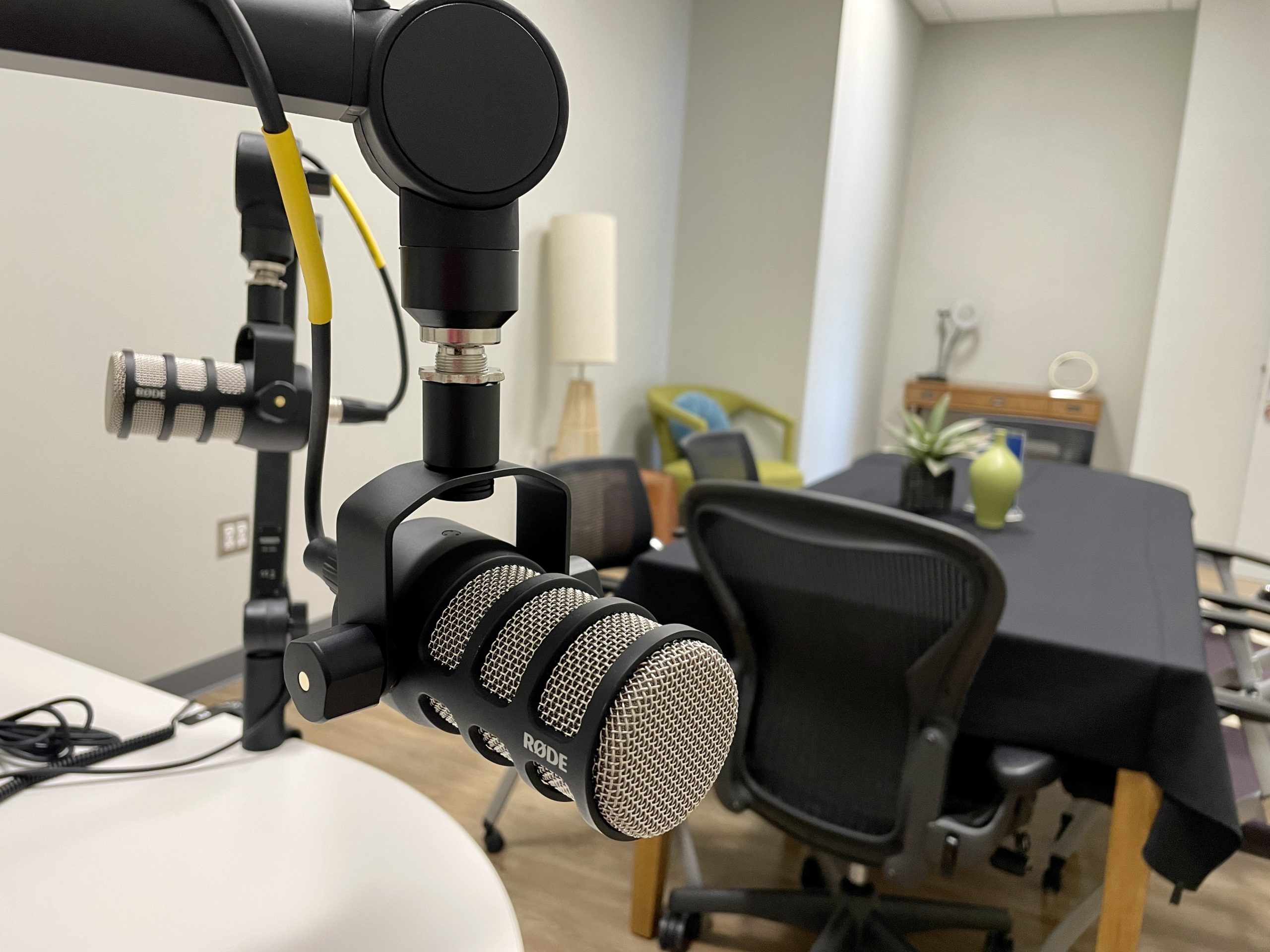 Close up of a podcast microphone with a meeting table in the background 